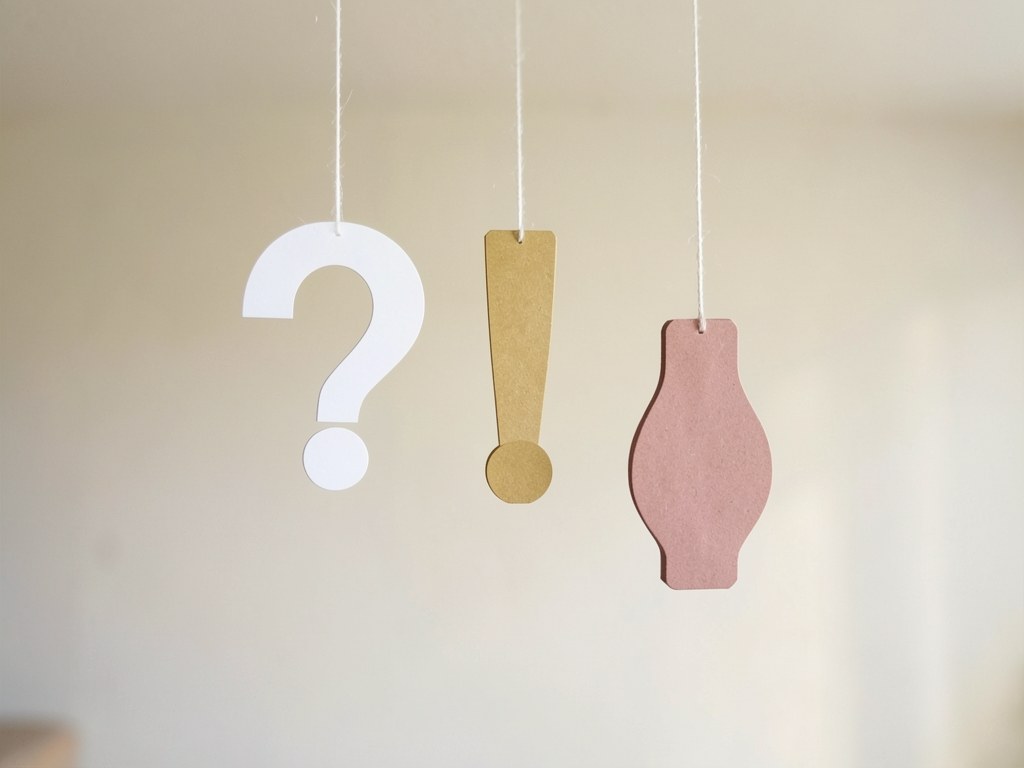 A hanging mobile with simple shapes of a question mark, an exclamation mark, and a lightbulb in the site's colors, representing common questions.